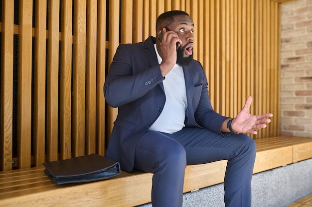 A dark-skinned businessman talking on the phone and looking involved