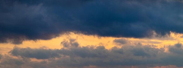 Dark storm clouds illuminated by the bright evening sun panorama