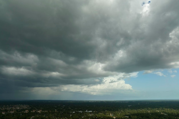 Dark stormy clouds forming on gloomy sky before heavy rainfall over suburban town area