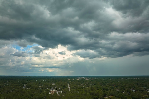 Dark stormy clouds forming on gloomy sky before heavy rainfall over suburban town area