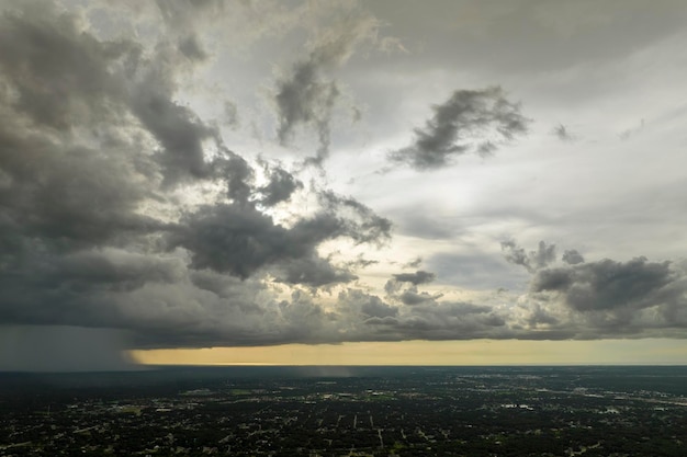 Dark stormy clouds forming on gloomy sky during heavy rainfall season over suburban town area