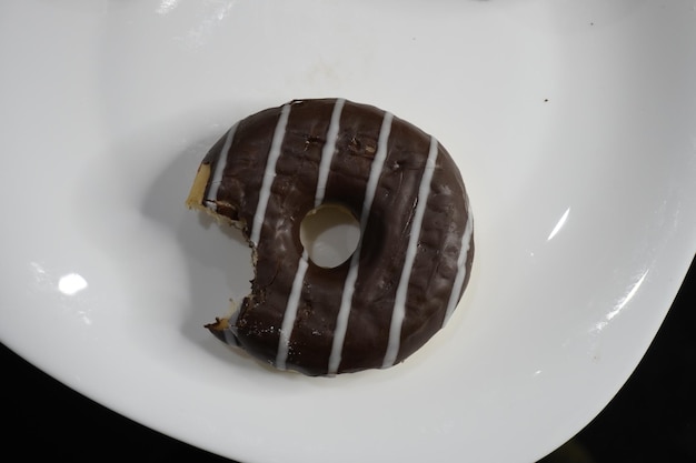 Dark and white chocolate donut with bite on plate