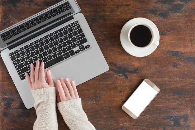 Dark wooden office desk table with laptop computer, mobile phone. Top view and flat lay with copy space, winter background