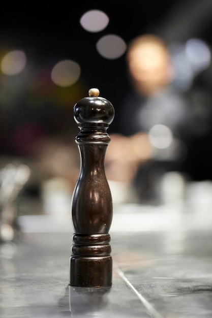 dark wooden pepper grinder on the table, blurred background. wooden salt shaker on bokeh background.