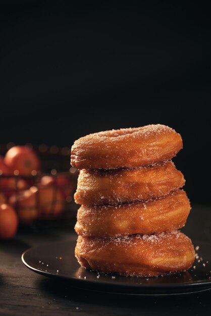 On a dark wooden surface with a black background donuts are stacked