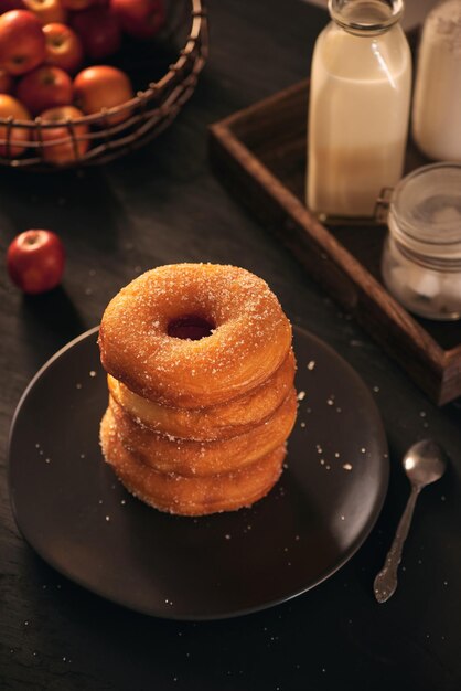 On a dark wooden surface with a black background donuts are stacked