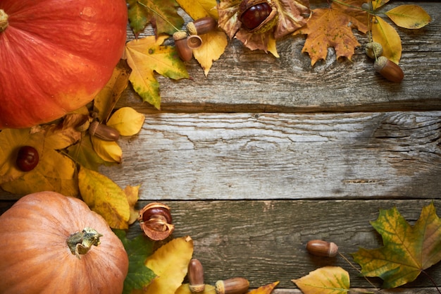 dark wooden surface with pumpkins, withered leaves, acorns and chestnuts, thanksgiving background