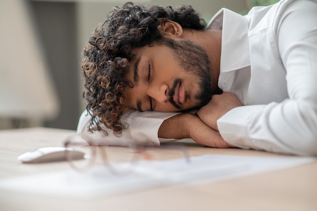 Darkhaired businessman sitting at the table and napping