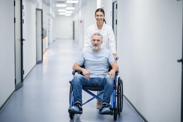 Darkhaired nurse carrying the wheelchair with a patient