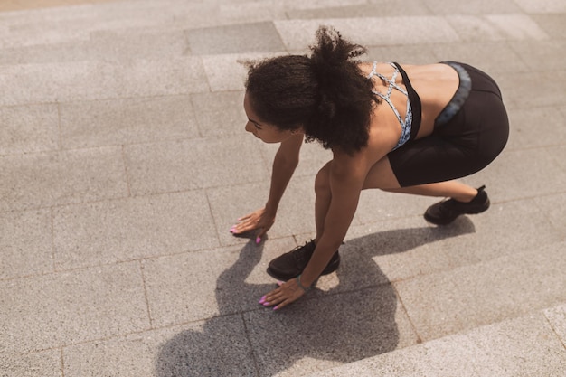 Darkhaired slim girl having a workout on the steps outside