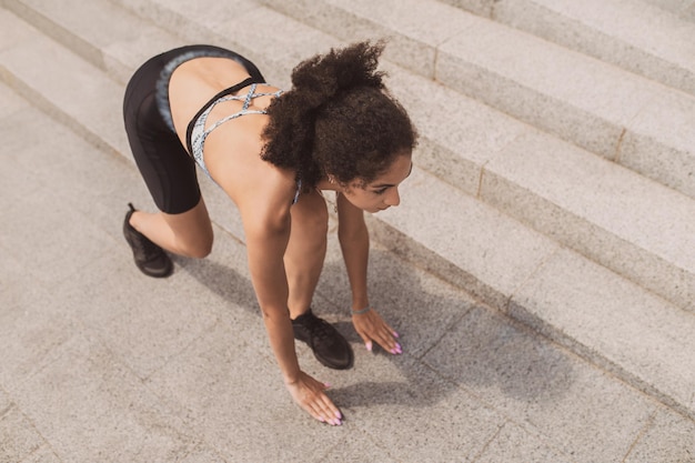 Darkhaired slim girl having a workout on the steps outside