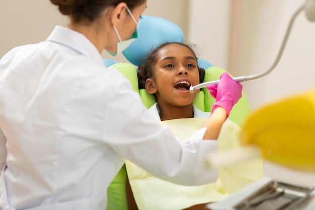 Darkhaired woman doctor leaning over little patient