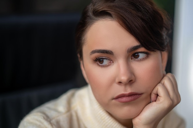 A darkhaired woman looking aside with a thoughtful view