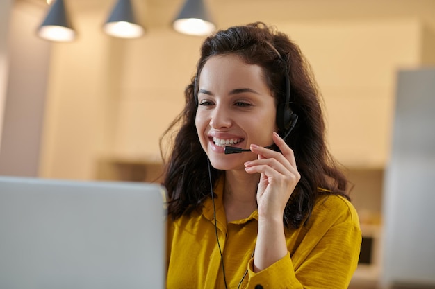 Darkhaired woman in a mustard shirt at her working place