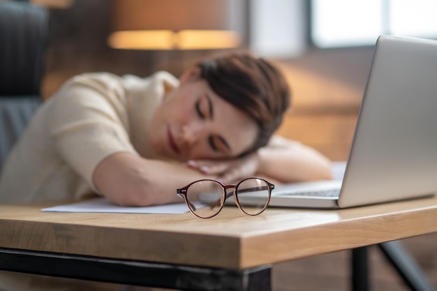 A darkhaired woman napping at the laptop after a hard day