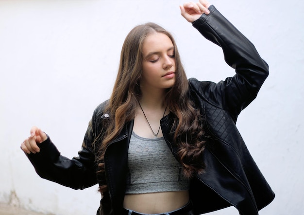 A darkhaired young girl in a black leather jacket is dancing