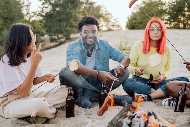 Darkskinned smiling man sits next to two beautiful white women