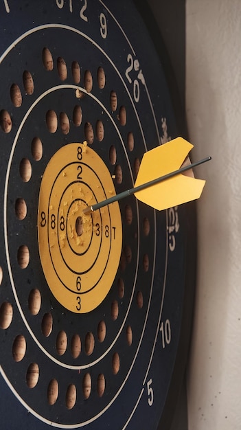 Photo dartboard with arrow inside of yellow punched paper for setup business objective target and goal co