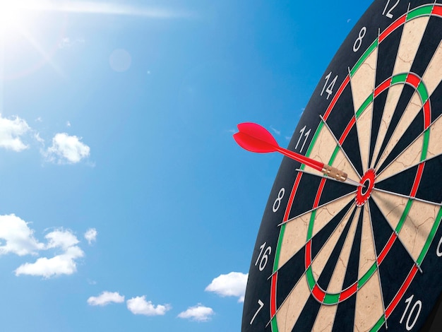 Darts with dartboard with blue sky background concept for hitting target goal and success