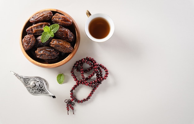 Dates fruit aladdin lamp and rosary beads on gray background