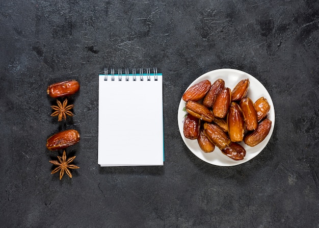 Dates fruit on plate with blank notepad 