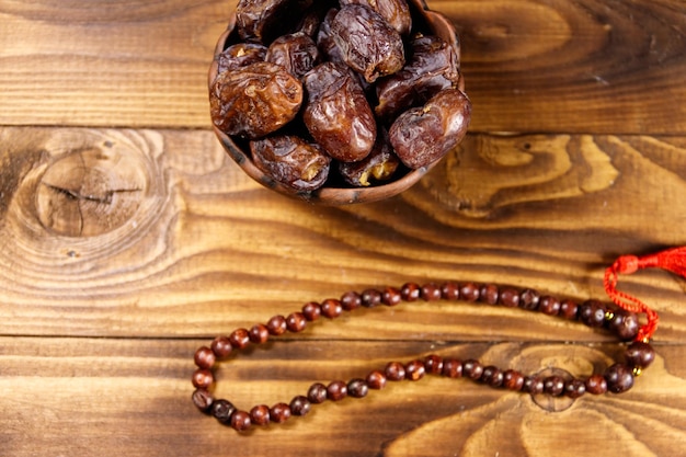 Dates fruit and rosary on wooden table Top view