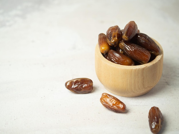 Dates in a wooden bowl on a gray concrete table copy space