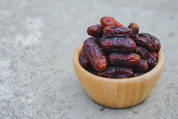 Dates in a wooden cup on a cement floor are highenergy fruits.