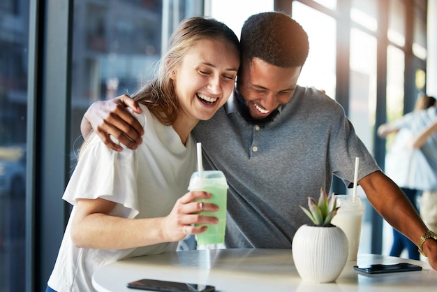 Dating restaurant and couple with smoothie drink hugging having fun and laughing together on romantic date Love relationship and interracial couple enjoying milkshake cocktail and juice in cafe