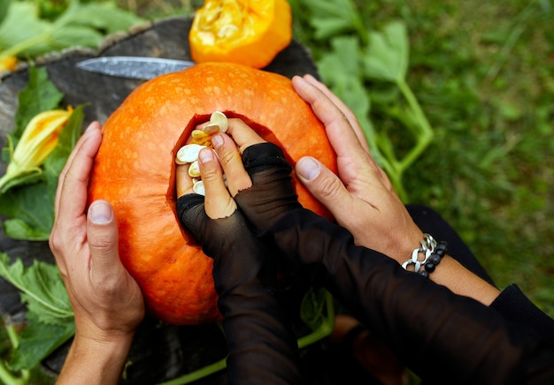 Daughter and father hands pulls seeds and fibrous material pumpkin before carving for Halloween, Prepares Jack o'Lantern. Decoration for party, Little family helper, Top view, close up,, copy space