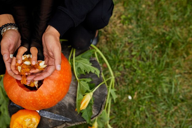 Daughter and father hands who pulls seeds and fibrous material from a pumpkin before carving for Halloween. Prepares Jack o'Lantern.