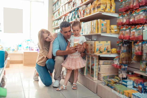 Daughter feeling curious while choosing food for parrot with parents