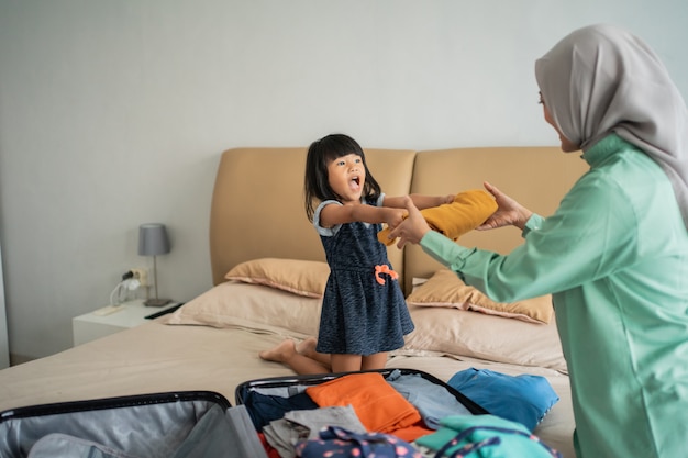 Daughter gives clothes to her mother who prepares suitcase