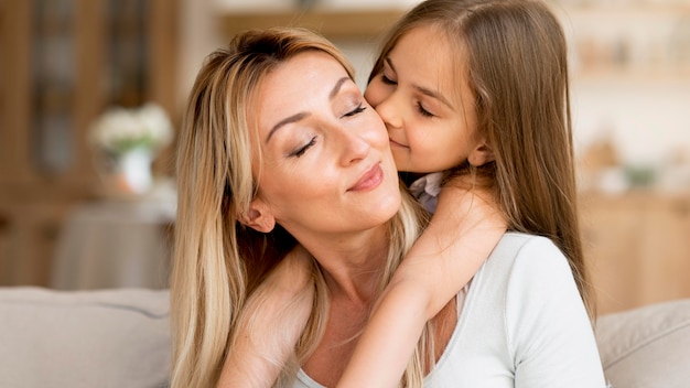 Photo daughter kissing her mother at home