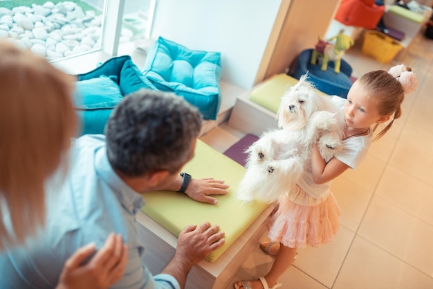 Daughter lifting cute fluffy dog and talking to parents