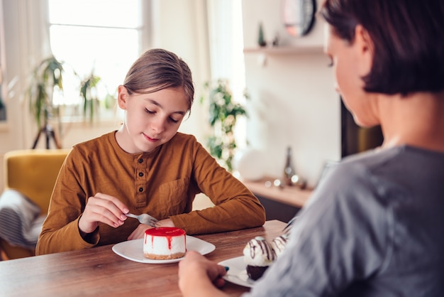 Daughter and mother eating cake at home