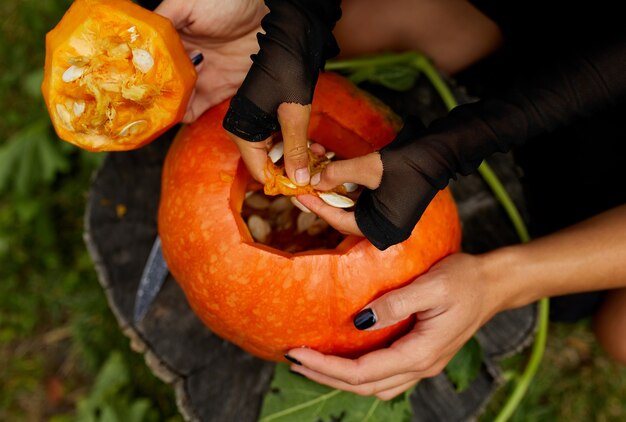 Daughter and mother hands carving pumpkin for Halloween