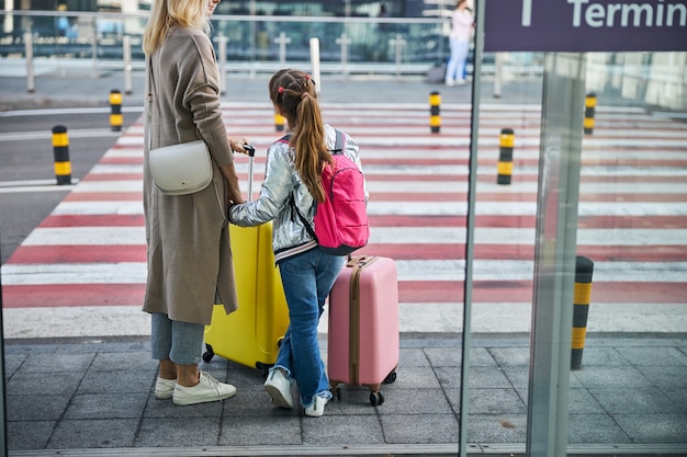 Daughter and mother holding bags in front of the road