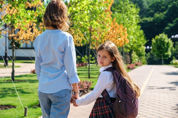 Daughter and mother walking together to school down the street