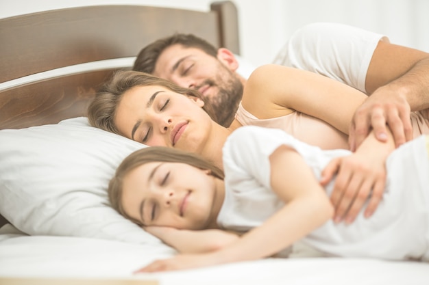 The daughter and parents sleeping in the bed