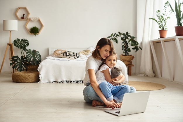 Daughter plays with mom and cat while mom works on computer