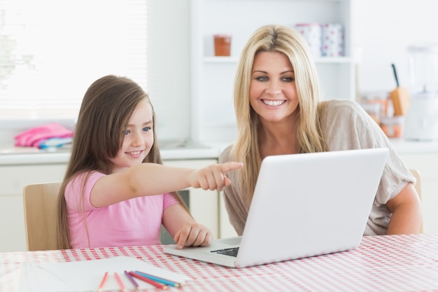 Daughter pointing at laptop with mother