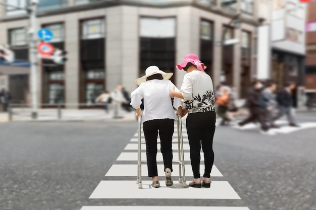 Daughter take care elderly woman walking on street in strong sunlight