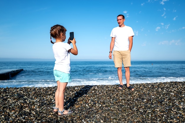 Daughter takes pictures of dad and shoots video on the phone as he is resting at sea