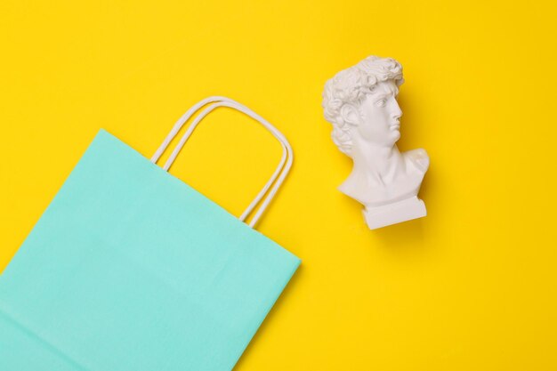 Photo david bust with shopping bag on yellow background minimal still life flat lay