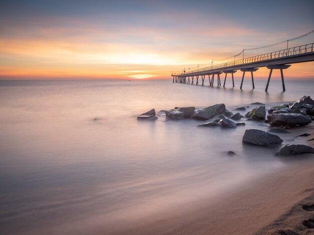 Dawn on the beach with ancient oil bridge, silk effect - (Pont del Petroli, Badalona, Spain)