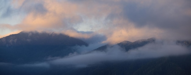 Dawn in the mountains fog and clouds on the peaks panoramic