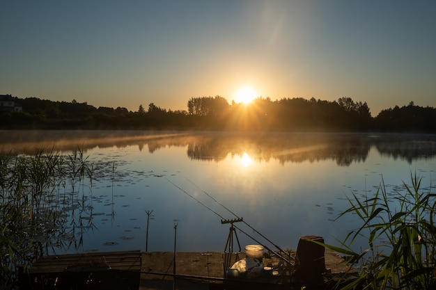 At dawn, two fishing rods are installed on the pier to catch fish on the lake