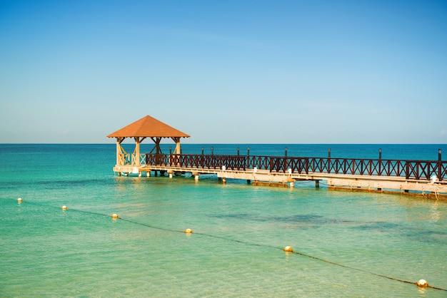 Dead Calm. Wooden pier, turquoise sea, blue horizon and clear cloudless sky.