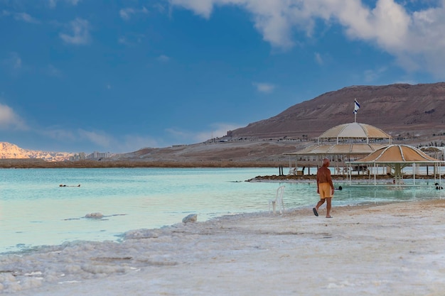 Dead Sea coastline Israel Sea season summer in city Ein Bokek Waterscape of seashore Man floating in the waters of the Dead Sea people enjoying a moment of relaxation Tropical landscape